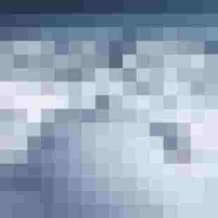 Zwei Personen gehen auf einem schneebedeckten Berggrat zwischen hohen alpinen Gipfeln